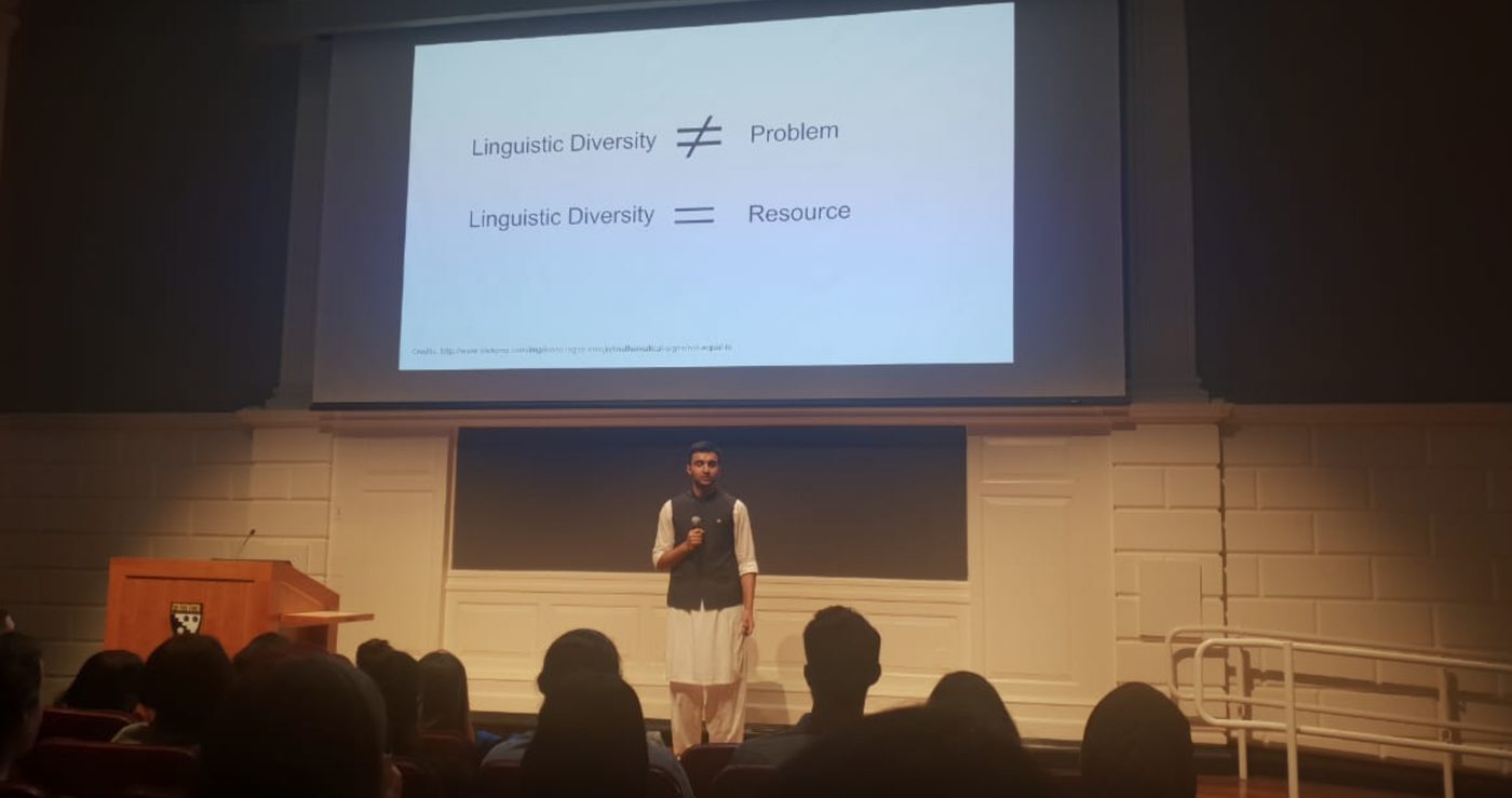 On stage beneath a slide reading: linguistic diversity is not a problem, linguistic diversity is a resource